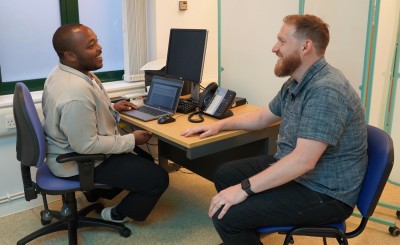 Two men are sitting in a doctor's room, talking