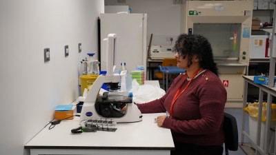 Prof Mona Bafadhel sits at a computer in a laboratory.JPG